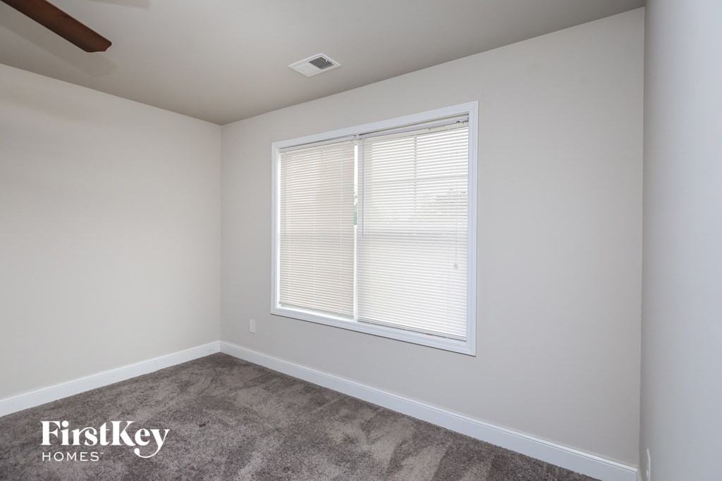 a bedroom with a large window and a carpeted floor