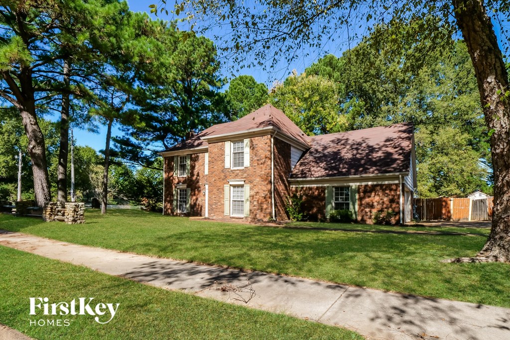 A brick house with a white door and a tree in front of it.