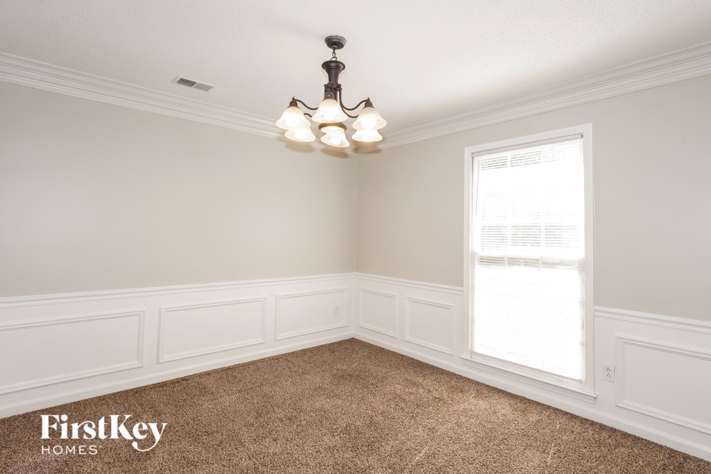 A room with a chandelier and a window with blinds.