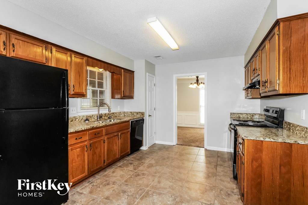 A kitchen with a black fridge and wooden cabinets.
