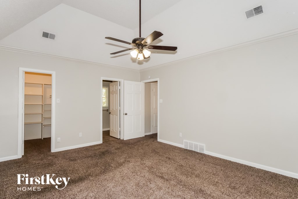 A room with a ceiling fan and carpeted floor.