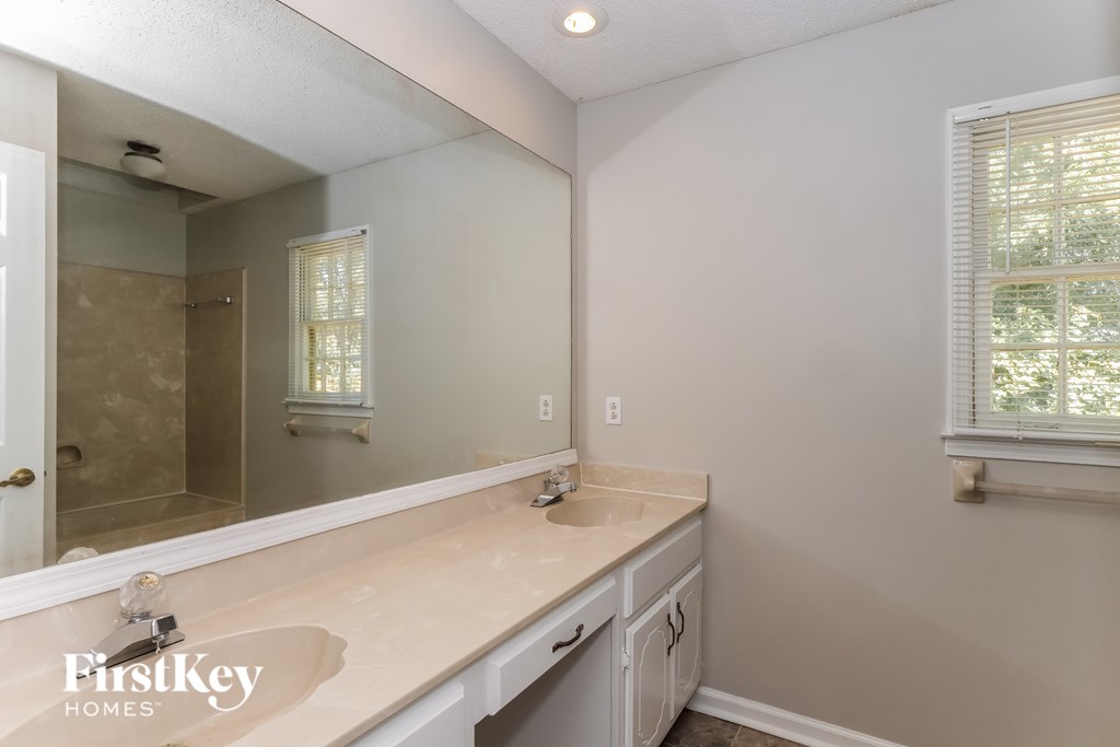 A bathroom with a sink, mirror, and a window.