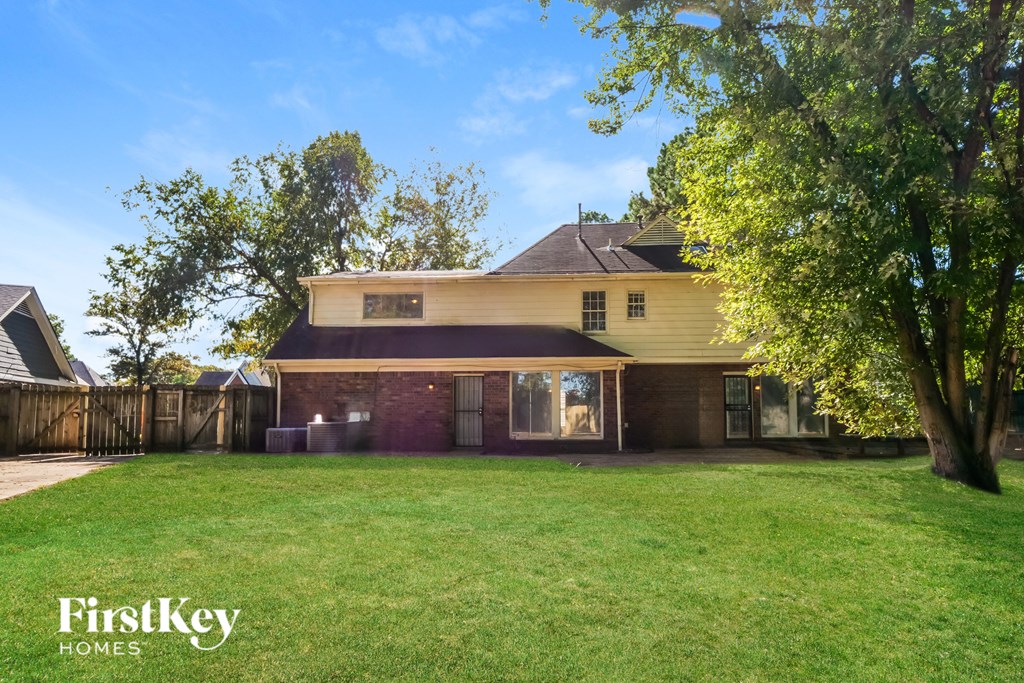 A house with a well-kept lawn and trees in front of it.