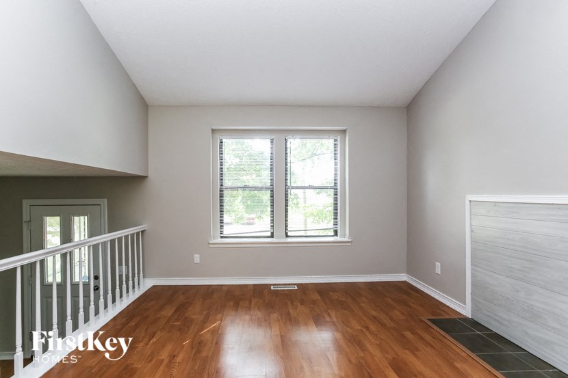 an empty living room with wood floors and a window