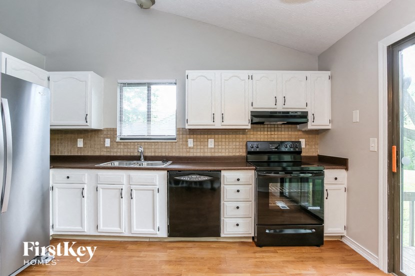 a white kitchen with black appliances and white cabinets