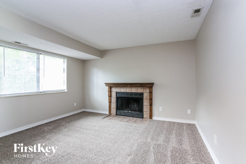 an empty living room with a fireplace and a window