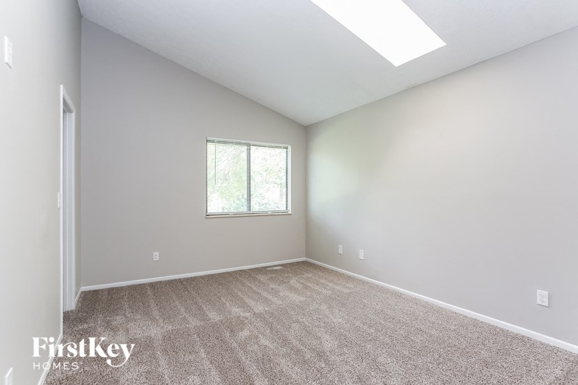 the living room of a new home with carpet and a window