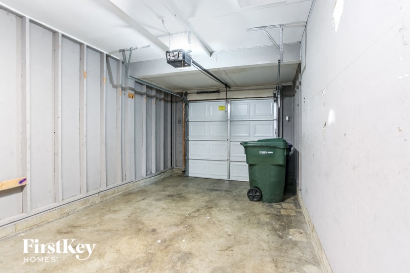 a garage with white walls and a green trash can
