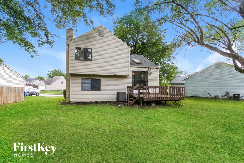 a backyard with a white house and a wooden deck
