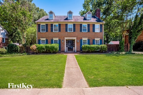 a large brick house with blue shutters and a lawn