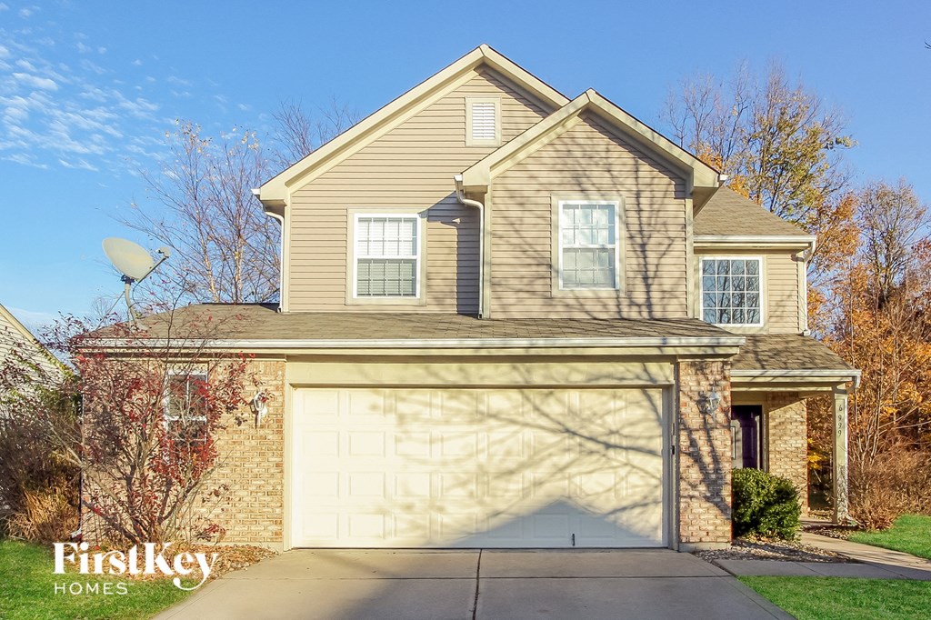 A house with a garage and a driveway in front of it.