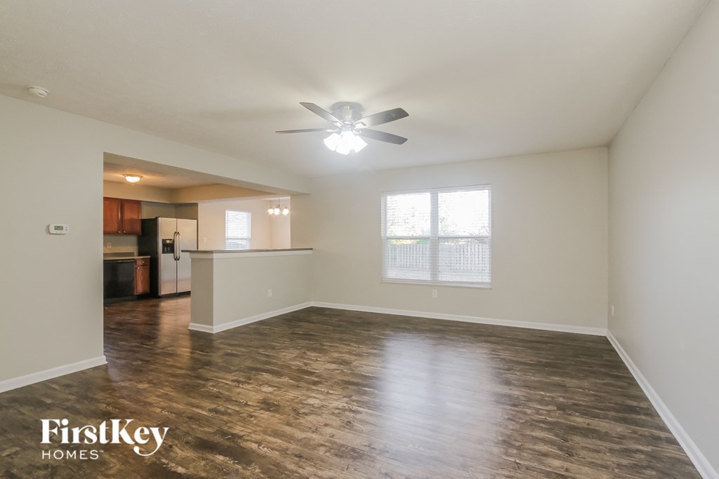 A spacious room with wooden flooring and a ceiling fan.