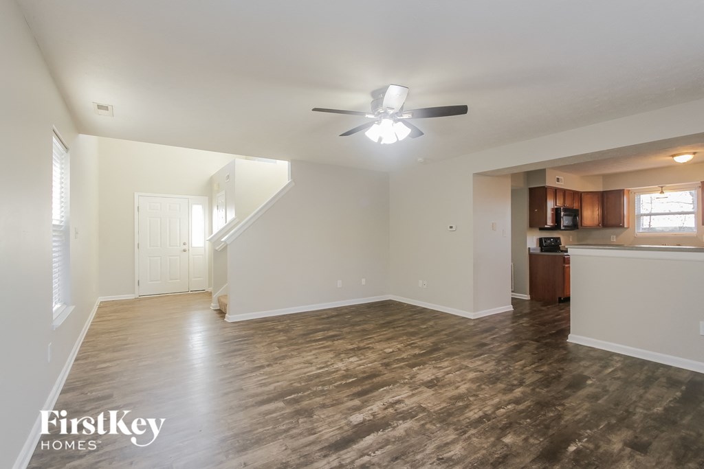 A spacious room with wooden floors and a ceiling fan.