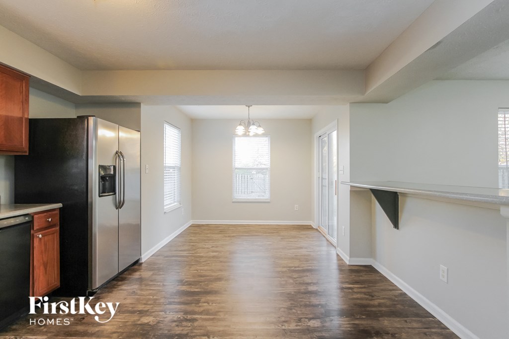 A kitchen with a refrigerator, cabinets, and a window.