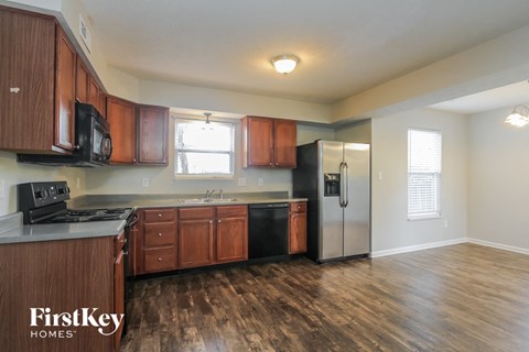 A kitchen with wooden cabinets and a black refrigerator.