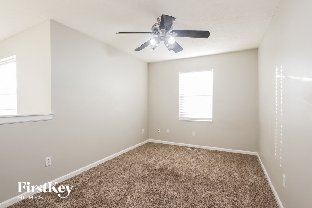 A room with a carpet floor and a ceiling fan.
