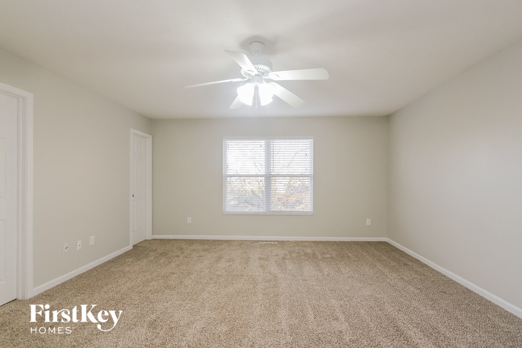 A spacious room with a carpeted floor and a ceiling fan.