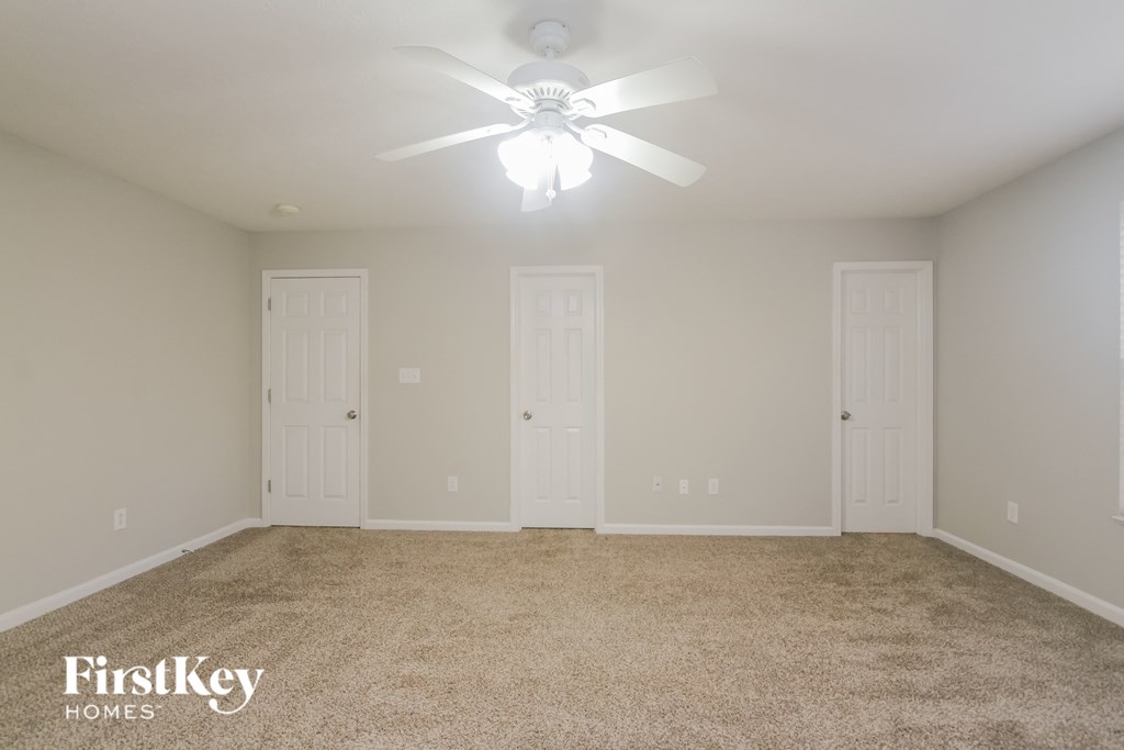 A room with a carpeted floor and a ceiling fan.