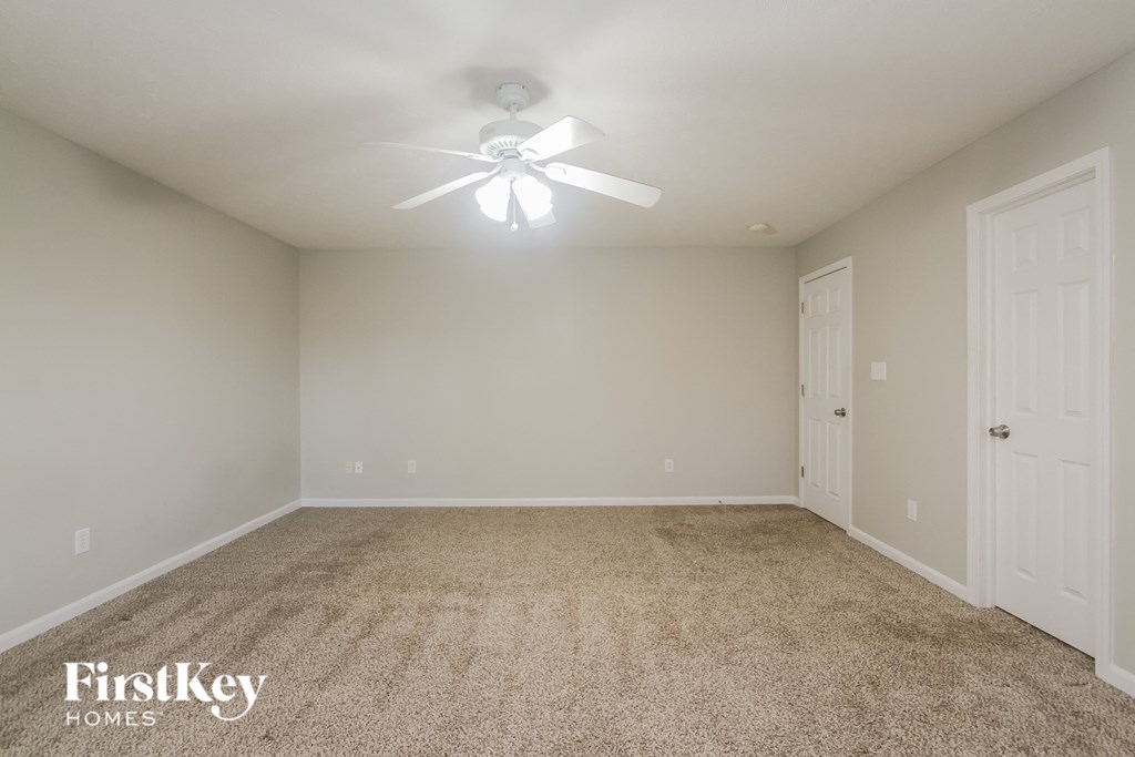 A spacious room with a carpeted floor and a ceiling fan.