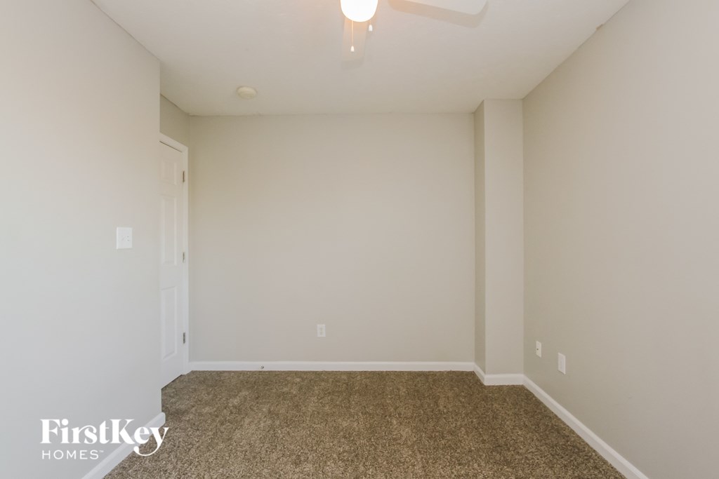 A room with a carpeted floor and a ceiling fan.