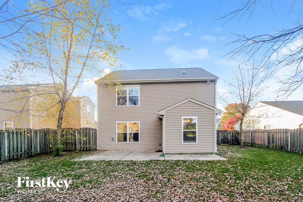 A house with a fence and trees in the background.
