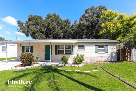 a small white house with green shutters and a grassy yard