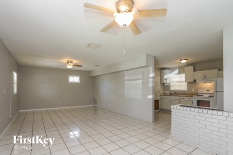 an empty living room and kitchen with a ceiling fan