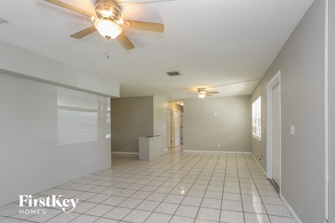 an empty living room with a ceiling fan and a tile floor