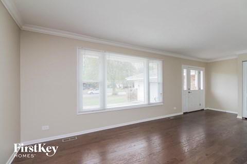 the living room of a home with a large window and wooden floors