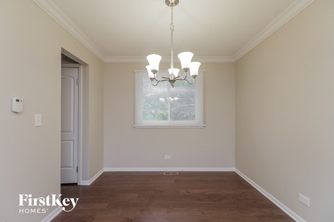 a empty dining room with a window and a chandelier