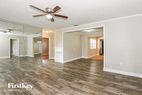 an empty living room with a ceiling fan and a large mirror