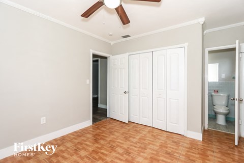 a bedroom with two closets and a toilet and a ceiling fan