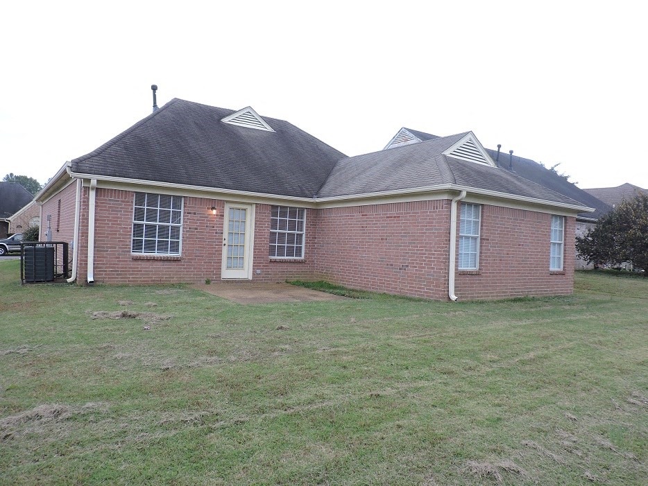 A red brick house with a black roof and white trim.