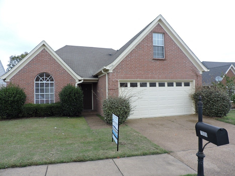 A brick house with a white garage door and a mailbox.