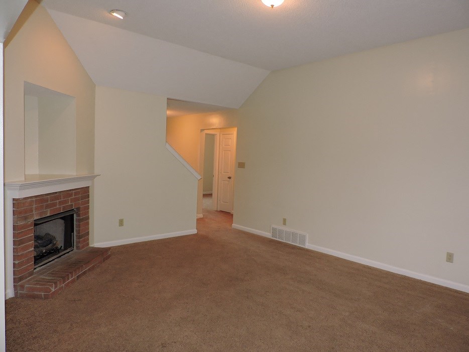 A living room with a fireplace and a carpeted floor.