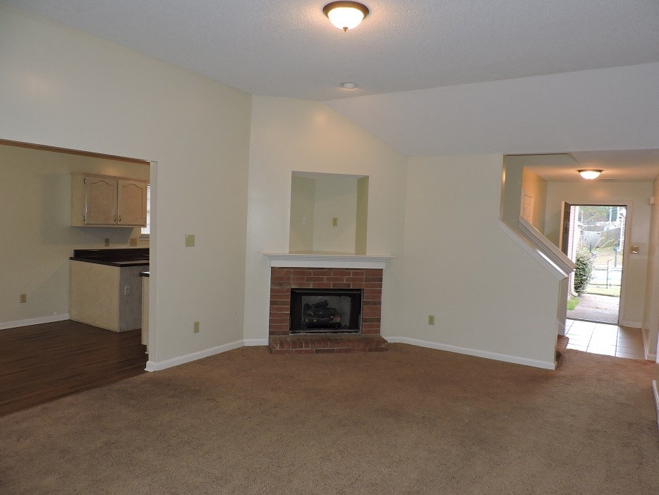 A living room with a fireplace and a staircase.