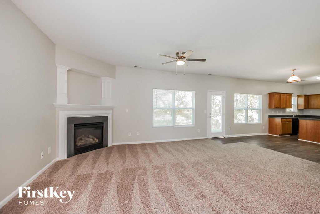 an empty living room with a fireplace and a ceiling fan