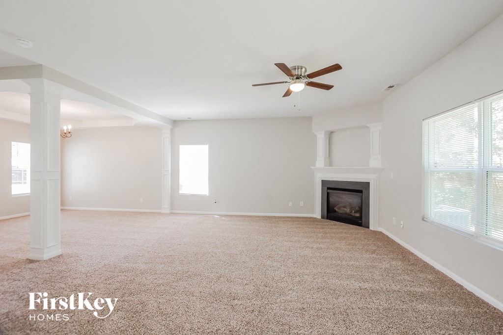 an empty living room with a ceiling fan and a fireplace