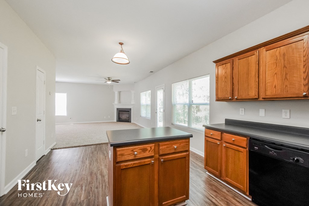 an empty kitchen with wooden cabinets and a black dishwasher and a fireplace