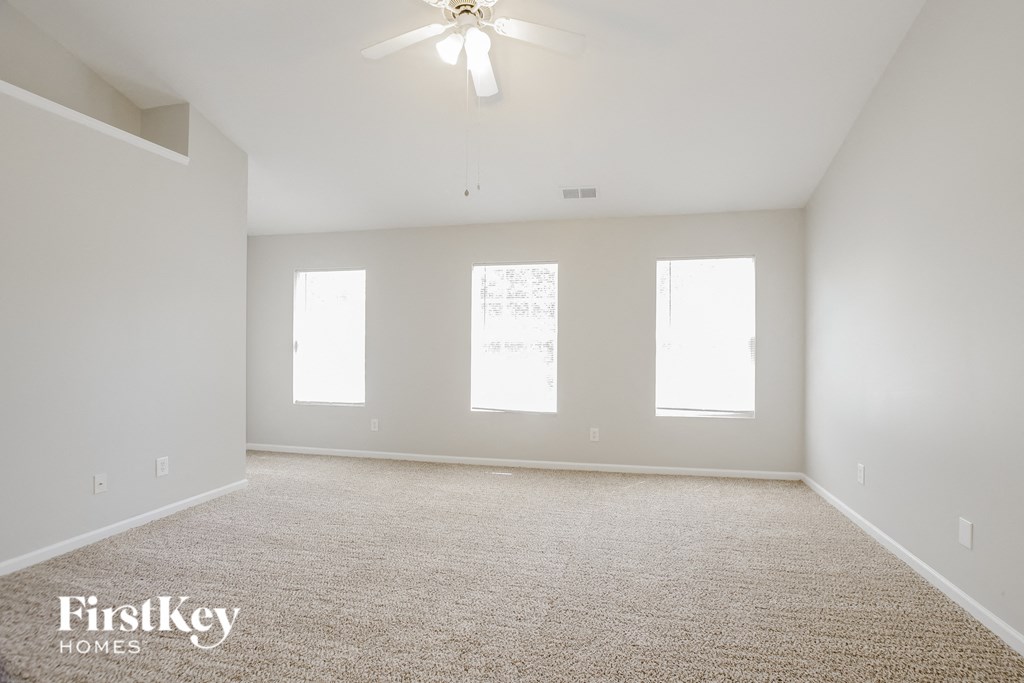 a spacious living room with white walls and a ceiling fan