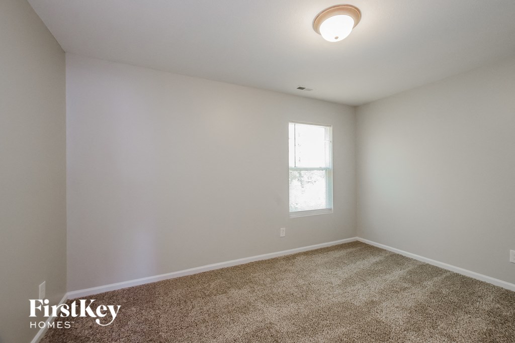 a bedroom with white walls and carpet and a window