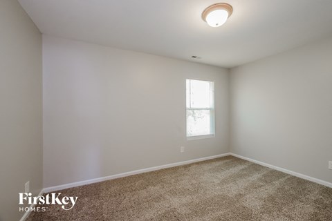 a bedroom with white walls and carpet and a window