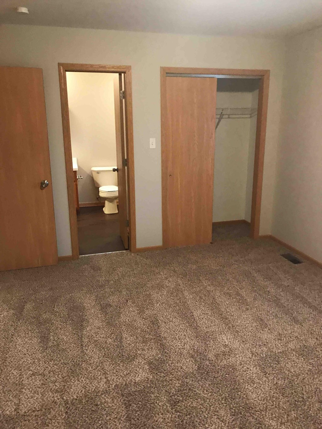 a room with a carpeted floor and two doors and a bathroom