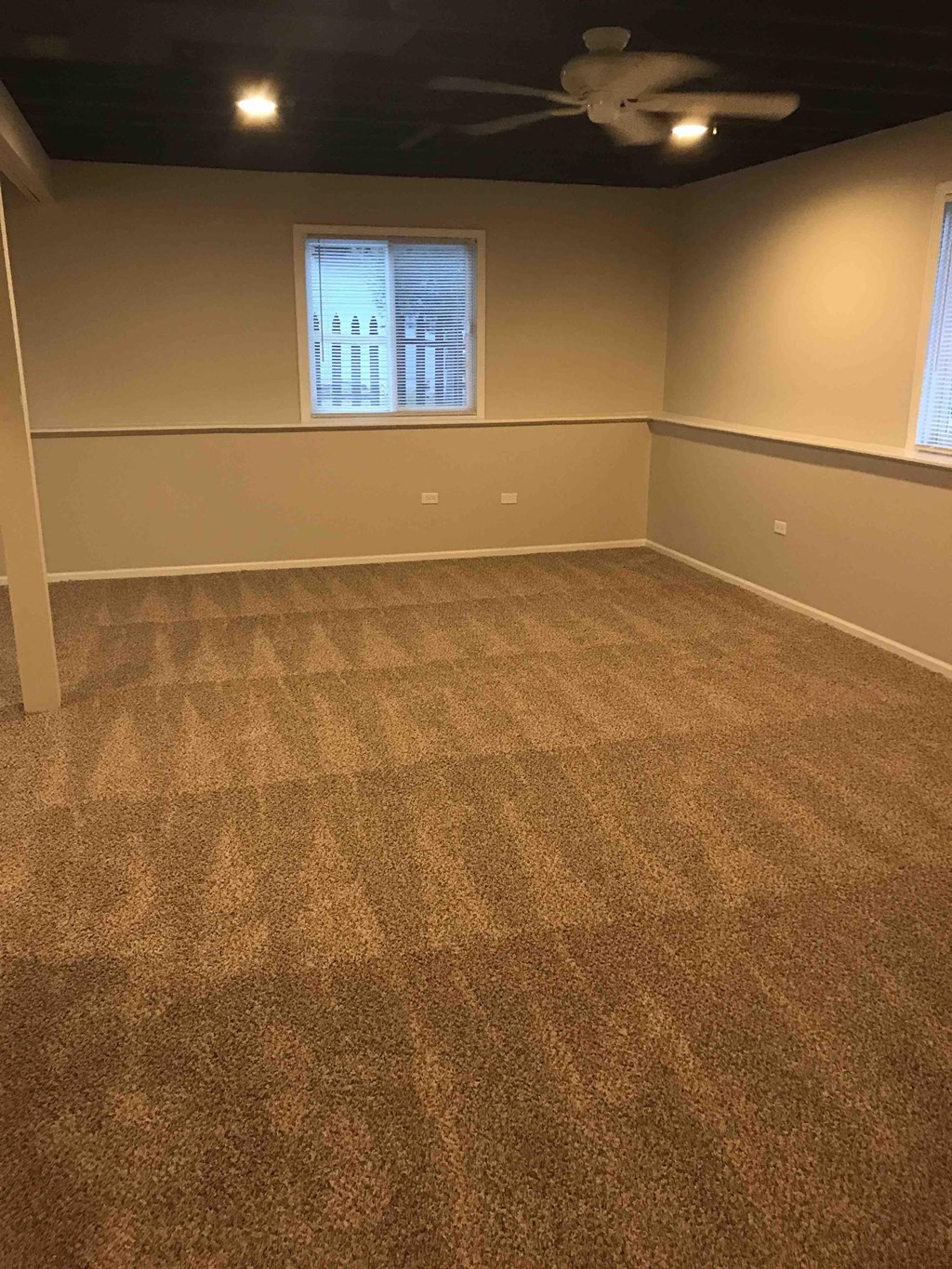an empty room with carpet and a ceiling fan