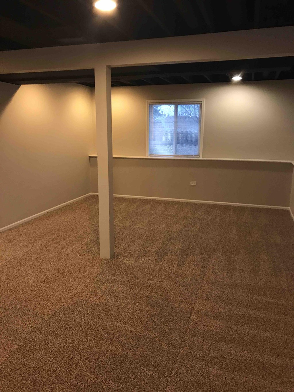a empty basement with a window and a carpeted floor