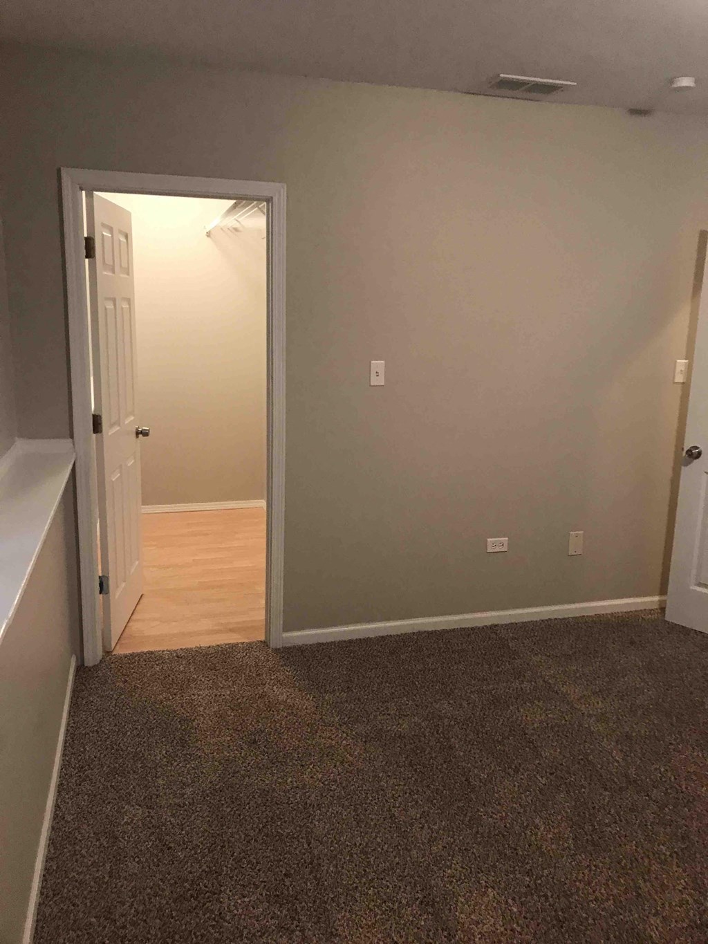 a hallway with an open door and a carpeted floor