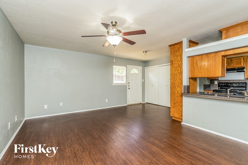 an empty living room with wood flooring and a ceiling fan