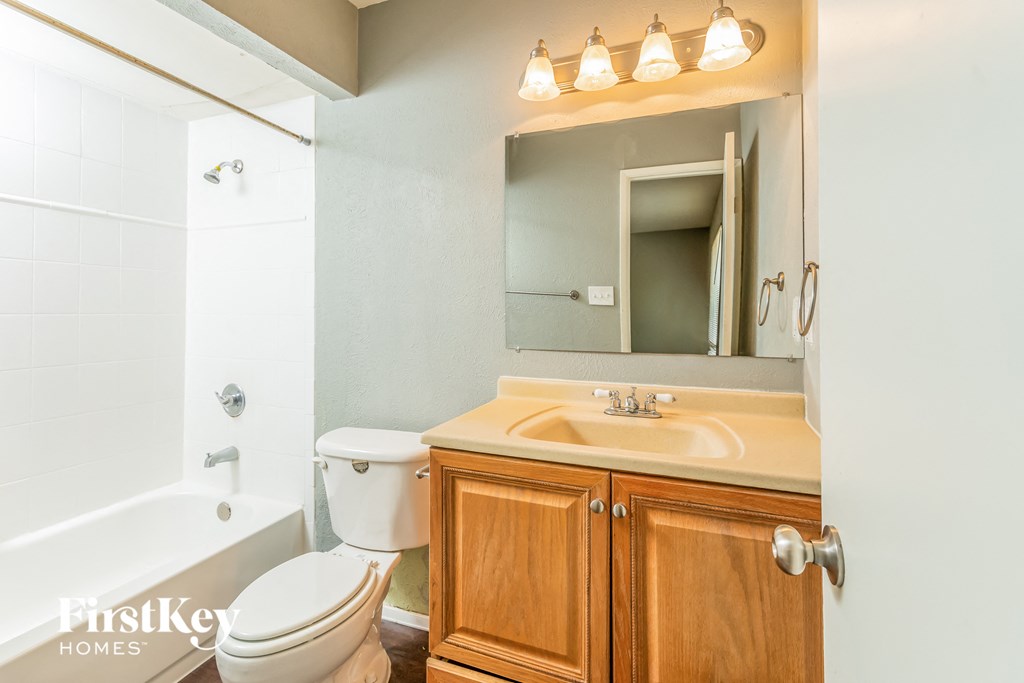 a bathroom with a toilet sink and mirror and a tub