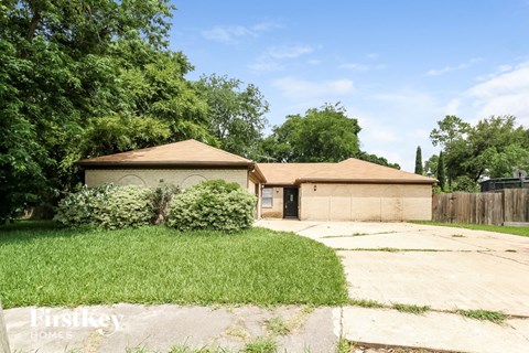 A house with a brown roof and a garage is surrounded by greenery.
