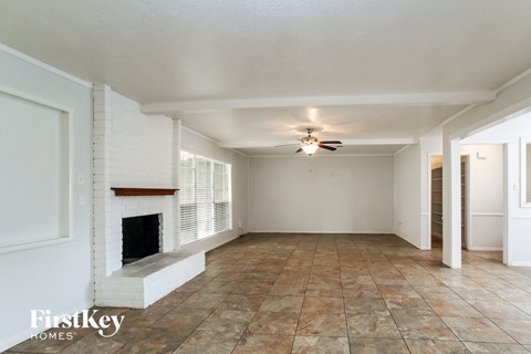 A spacious room with a fireplace and tiled flooring.